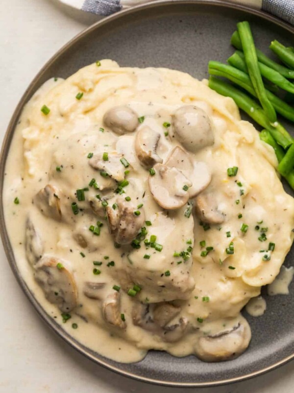 Instant Pot Chicken in mushroom sauce served over a bed of mashed potatoes on a grey plate with steamed green beans