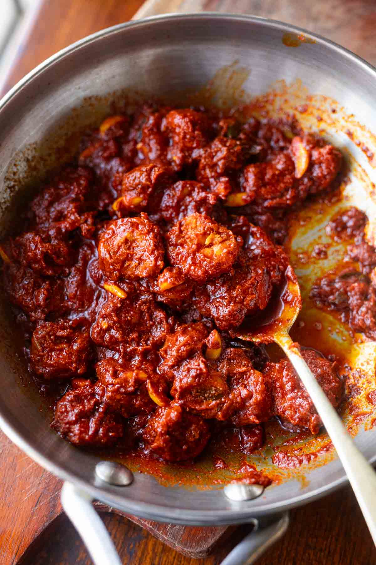 Prawn Pickle in a pan with a spoon showing a pickled prawn