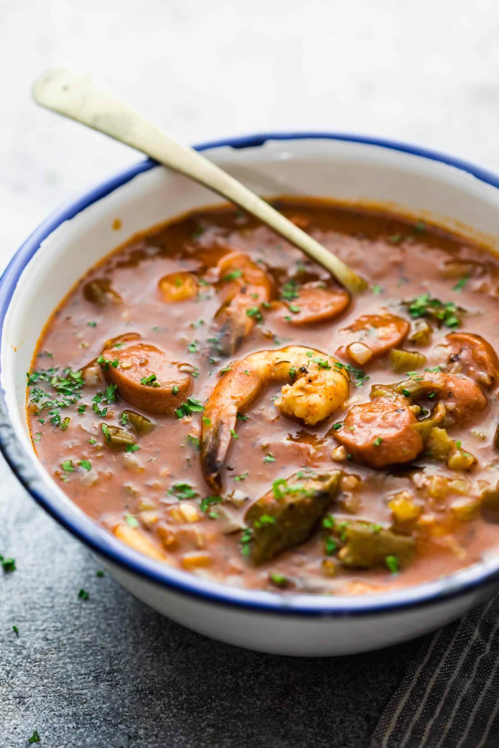 Side angle of New Orleans Shrimp Sausage Gumbo in an enamel bowl with a spoon