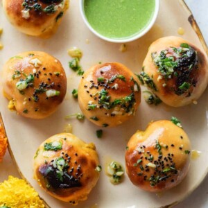 Naan bombs served on a platter with mint chutney and marigold flowers strewn about