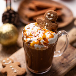 salted caramel hot chocolate served in a mug and topped with whipped cream, caramel sauce and a gingerbread cookie