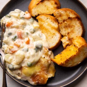 Veg Au Gratin served on a plate with slices of garlic bread