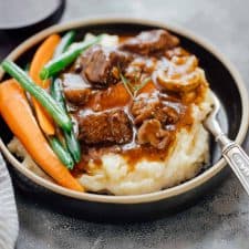 Pressure Cooker Beef Bourguignon served with mashed potatoes and grilled veggies in a black plate.
