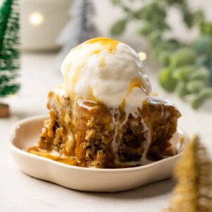 Sticky Toffee Pudding served on a white dessert plate topped with vanilla ice cream and toffee sauce