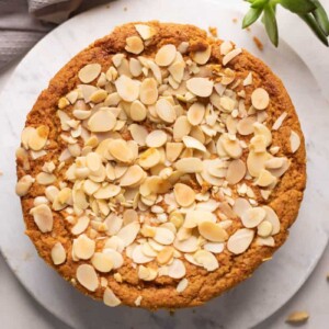 Mawa Cake served on a white platter with sliced almonds on the side