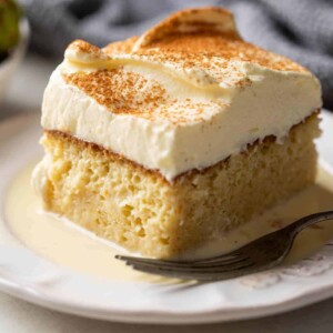 Eggnog tres leches served with strawberries on the side on a white plate