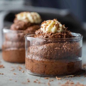 eggless chocolate mousse served in glass jars topped with whipped cream and a sprinkle of grated chocolate