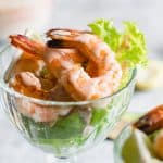 Retro prawn cocktail served in stem glasses with marie rose sauce drizzled over them.