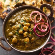a bowl of chole palak served along with onion rounds and naan