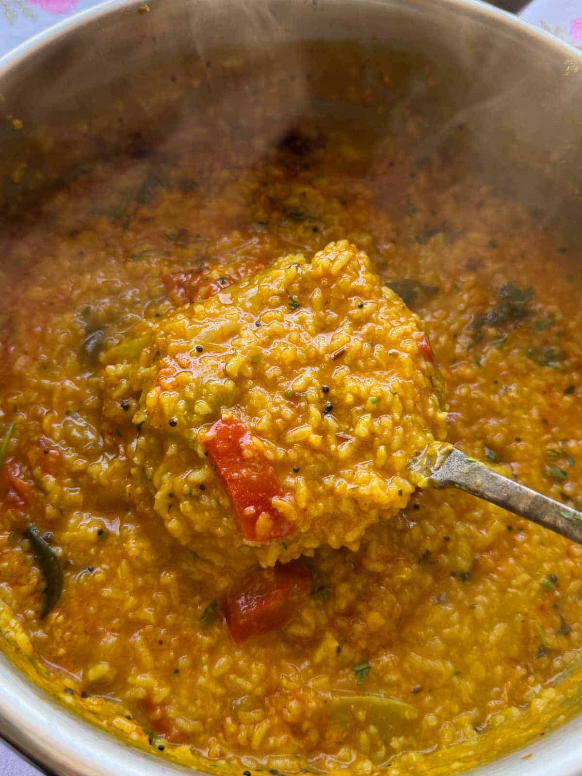 one pot sambar rice scooped up in a ladle from the cooking pot