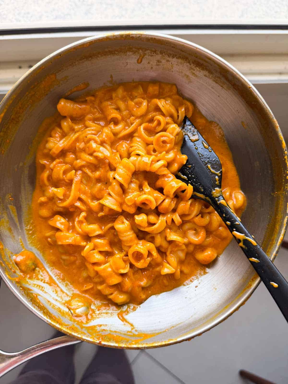 freshly made red pepper pasta still in the frying pan with a spatula