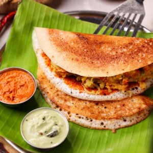 Serving mysore masala dosa with two chutneys on a banana leaf
