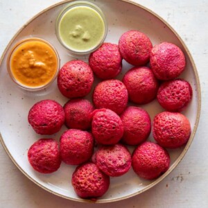 Beetroot Paniyaram served on a plate with coconut chutney and tomato chutney