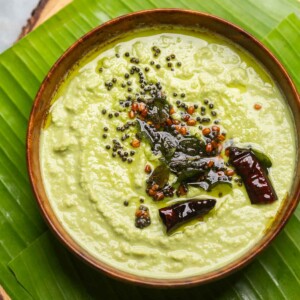 an image of coconut chutney made served in a bowl placed over a banana leaf platter