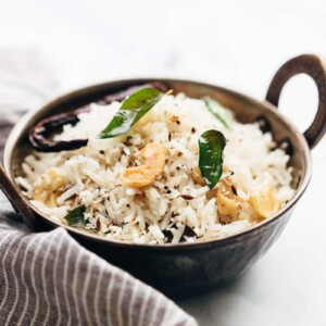 Coconut rice served in a kadhai topped with roasted cashews and curry leaves
