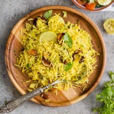 Flavorful lemon rice served on a wooden plate with a spoon.