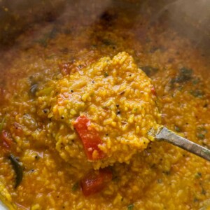 one pot sambar rice scooped up in a ladle from the cooking pot