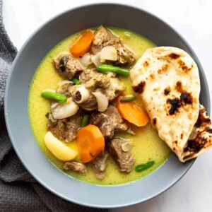 Mutton stew with coconut served in a bowl with naan bread