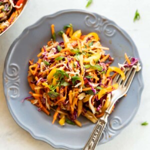 Asian Slaw in a grey bowl with fork on white background