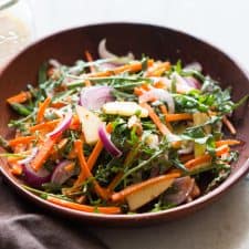 Apple Arugula Almond Salad with Orange Dressing served in a bowl.