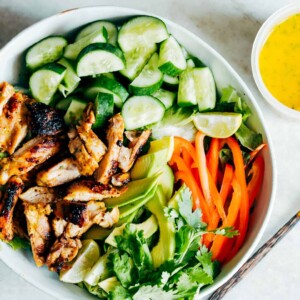 A bowl full of ingredients of the salad with a side of the dressing.