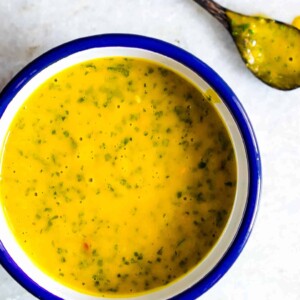 A creamy and smooth Mango Cilantro Salad Dressing in a blue and white bowl.