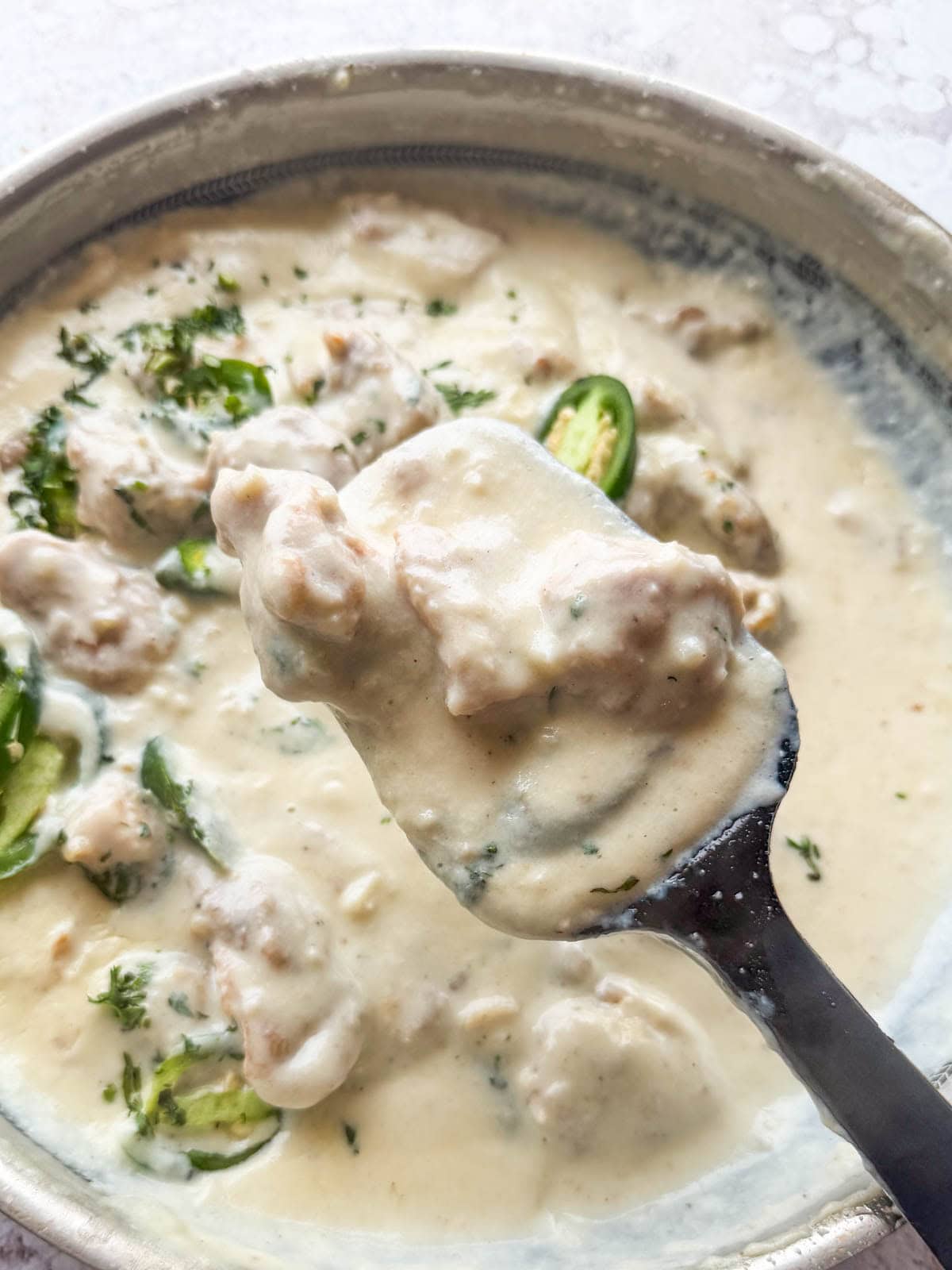japan chicken scooped up in a ladle to showcase it's color and texture