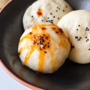 steamed buns or boazi served on a black plate with a drizzle of chilli oil