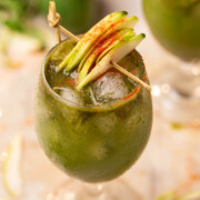 aam panna served in a glass and garnished with raw mango slices and chilli powder
