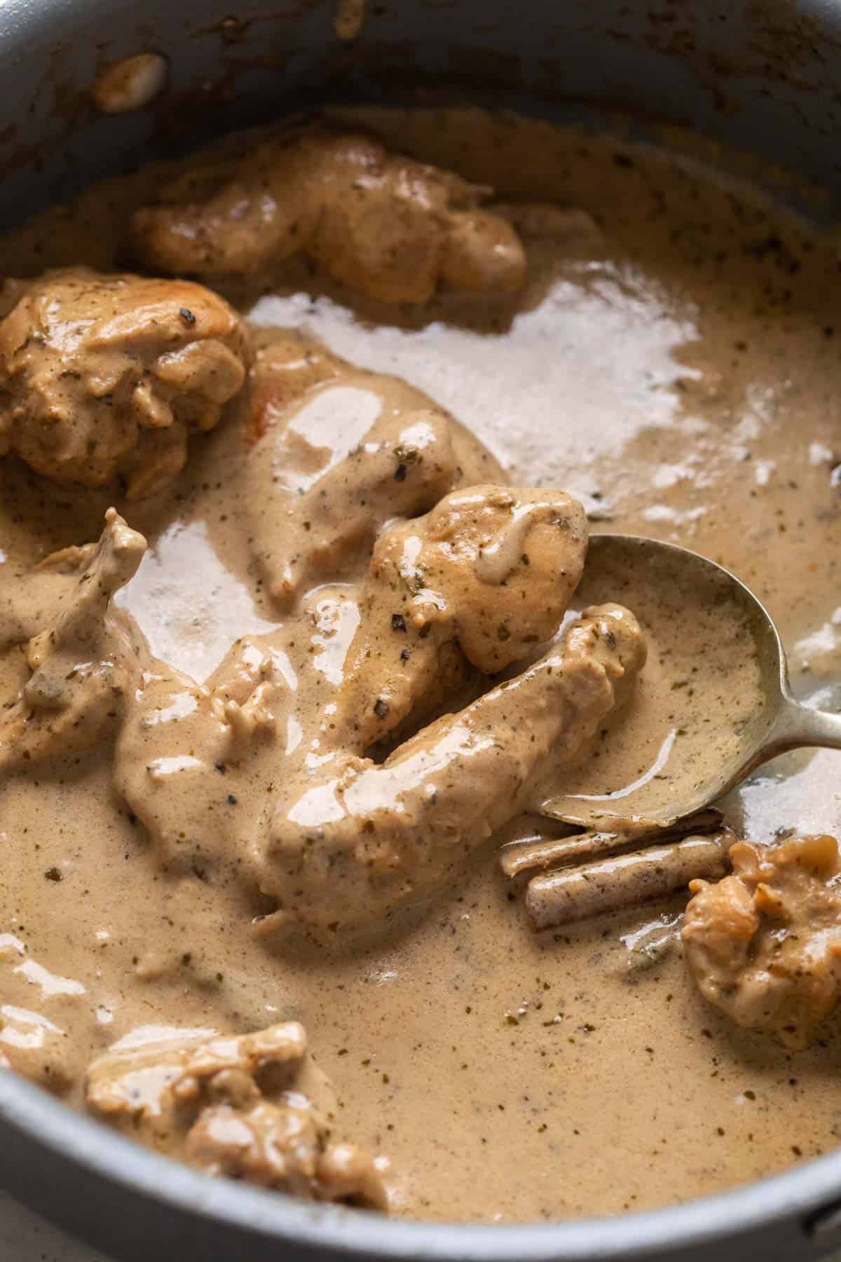 Chicken kali mirch pictured in the pan that it was cooked in with a spoon pooling up the gravy