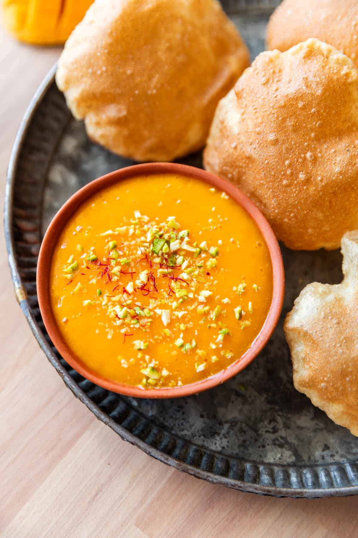 picture of aam ras on a plate with many puris