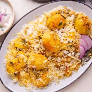 Egg Biryani served on a white platter with onion raita on the side