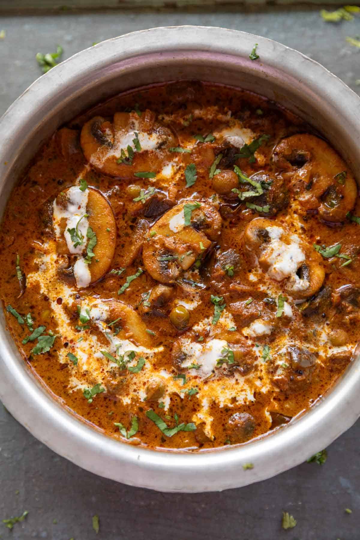 Restaurant-style mushroom masala with peas and herbs in a bowl.