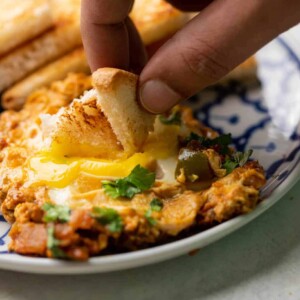 A slice of bread being dipped into the egg yolk