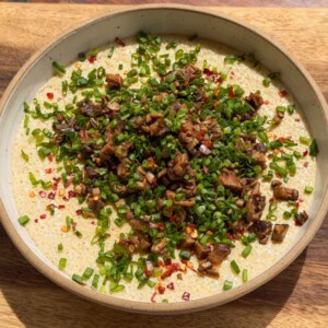 an image of chinese steamed eggs garnished with mushroom and spring onion ready to be eaten