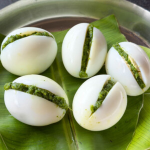 stuffed eggs served on a steel plate covered with banana leaf