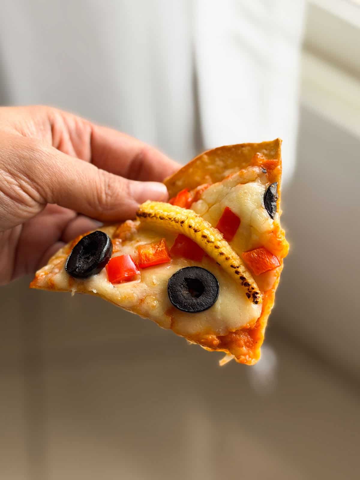 a person holding a slice of air fryer roti pizza