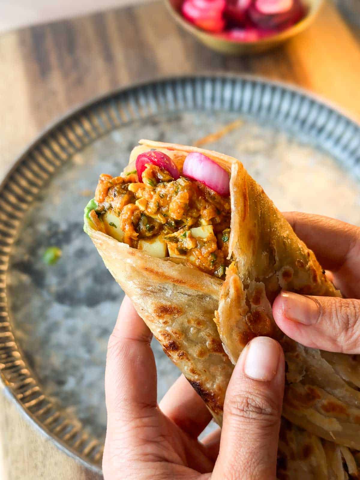 a person holding an assembled masala egg roll
