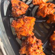 a close up image of tandoori chicken bites in the air basket